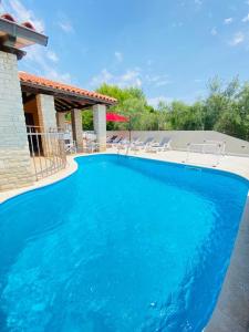 a large blue swimming pool with chairs next to a house at Villa Family in Medulin