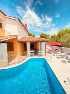 a swimming pool in front of a house with chairs at Villa Family in Medulin