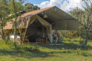 a man sitting in a tent in a field at Mara Siria Tented Camp & Cottages in Aitong