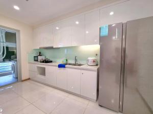 La cuisine est équipée de placards blancs et d'un réfrigérateur en acier inoxydable. dans l'établissement Happy Homes - Vinhomes Central Park, à Hô-Chi-Minh-Ville