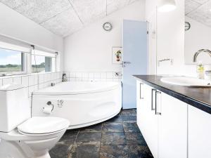 a white bathroom with a tub and a toilet at 6 person holiday home in Jerup in Jerup