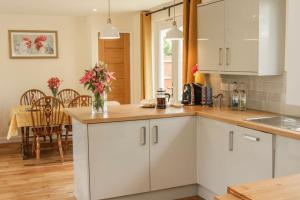 a kitchen with white cabinets and a dining room at Edge View Cottage in Church Stretton +9 photos