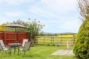 a garden with a table and chairs and an umbrella at Edge View Cottage in Church Stretton