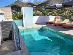 a swimming pool with an umbrella on a house at White Boutique Homes - Serenity in Metókhion Apisianá