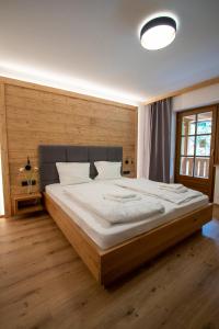 a bedroom with a large bed with a wooden wall at Sporthotel Dachstein West in Annaberg im Lammertal