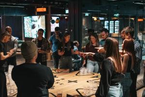 a group of people standing around a table in a room at Next House Copenhagen in Copenhagen