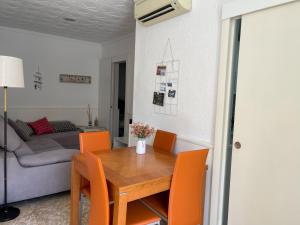 una sala da pranzo con tavolo in legno e sedie arancioni di Lleida 25, casa a planta baixa amb àmplia terrassa equipada amb barbacoa a Sant Carles de la Ràpita