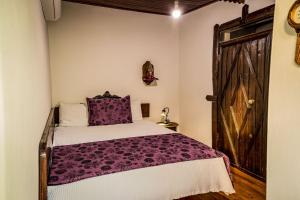 a bedroom with a bed with purple sheets and a wooden door at Stonehouse in Selçuk