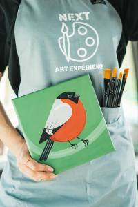 a woman holding a book with a bird on it at Next House Copenhagen in Copenhagen