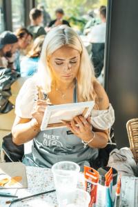 a woman sitting at a table looking at her tablet at Next House Copenhagen in Copenhagen