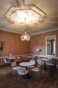 une salle à manger avec des tables et des chaises ainsi qu'un lustre dans l'établissement Château du Pont d'Oye, à Habay-la-Neuve