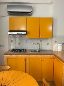 a kitchen with orange cabinets and a sink and a table at La Dimora del RE in Gaeta