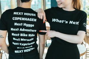 a couple holding up shirts that saynext house copenhagen next huge next appliance at Next House Copenhagen in Copenhagen