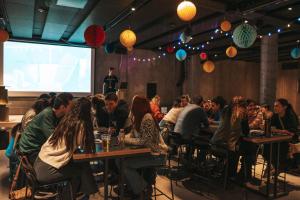 a group of people sitting at tables in a room with a presentation at Next House Copenhagen in Copenhagen