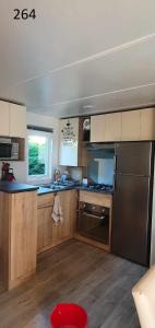 a kitchen with wooden cabinets and a stainless steel refrigerator at davorel mobil home in Les Mathes
