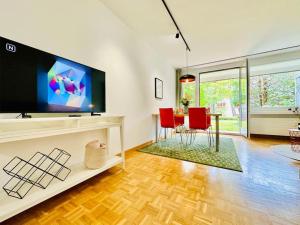 sala de estar con TV, mesa y sillas en New, central studio with garden terrace and much privacy en Zúrich