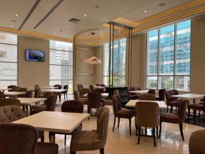 un restaurante con mesas, sillas y ventanas en Khalidia Palace Hotel Dubai, en Dubái
