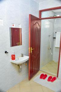 a bathroom with a sink and a shower with red slippers at Four seventy in Meru