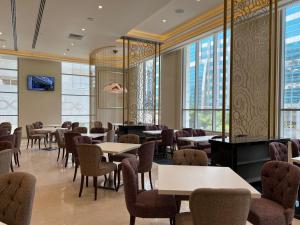 un comedor con mesas, sillas y ventanas en Khalidia Palace Hotel Dubai, en Dubái