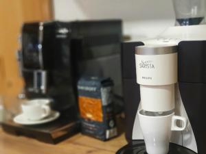 a coffee machine with a cup on a counter at Hanul Casa Alba Fehér Ház Fogadó in Periprava