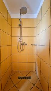 bagno con doccia e piastrelle gialle di Hanul Casa Alba Fehér Ház Fogadó a Periprava