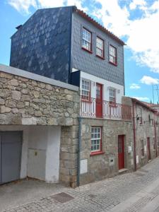 um edifício com um telhado azul e janelas vermelhas em TORREÃO HOUSE na Guarda