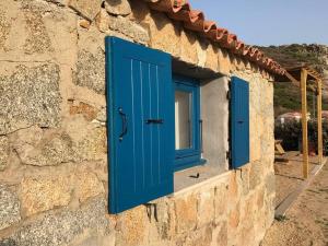 a window with blue doors on a stone building at Golfe de Sagone Plage du Liamone Maison pieds dans l'eau in Casaglione