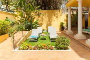 eine Terrasse mit Stühlen, einem Tisch und Blumen in der Unterkunft Hotel Boutique Villa Lorena by Charming Stay Adults Recommended in Málaga