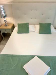 a large white bed with two green pillows on it at Eva beach hotel in Nydri