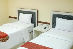 a hotel room with two beds and a table at Grand Buana Lestari Hotel in Duku