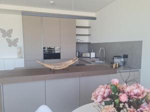 a kitchen with white cabinets and a vase of pink flowers at Luxury apartment Lisbon in Lisbon