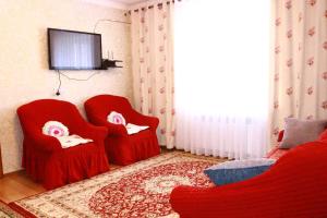 ein Wohnzimmer mit 2 roten Stühlen und einem TV in der Unterkunft Almaz Guesthouse Naryn in Orto-Saz