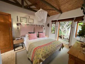 a bedroom with a bed with pink pillows and a window at Treetops Cottage in Cape Town