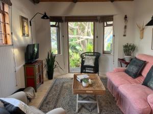 a living room with a pink couch and a table at Treetops Cottage in Cape Town