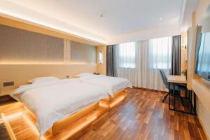 a bedroom with two beds and a desk and a television at Derreal Hotel - Beijing Shunyi Guozhan Branch in Beijing