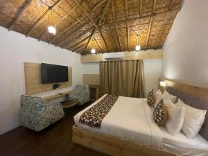 Corbett Selva Resort By DevStayZ في رامناجار: غرفة نوم بها سرير ومكتب وتلفزيون