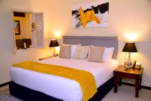 um quarto com uma grande cama branca e 2 candeeiros em The Emin Pasha Hotel & Spa, CityBlue Collection em Kampala