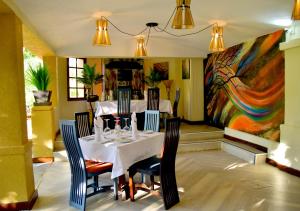 jadalnia ze stołem, krzesłami i obrazem w obiekcie The Emin Pasha Hotel & Spa, CityBlue Collection w mieście Kampala