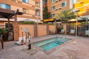 une piscine dans un hôtel avec un bâtiment dans l'établissement Courtyard by Marriott San Diego Oceanside, à Oceanside