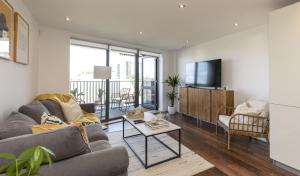 a living room with a couch and a tv at MODERN LUXE APT just 10 MINS from TOWER BRIDGE! EASY ACCESS TO TUBE AND BUS in London