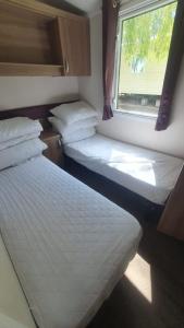 two beds in a small room with a window at Caravan 66 Kensington at Marton Mere Holiday Park Blackpool in Blackpool