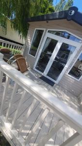a wooden deck with two chairs on a house at Caravan 66 Kensington at Marton Mere Holiday Park Blackpool in Blackpool