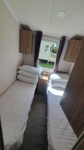 uma fila de camas num pequeno quarto em Caravan 66 Kensington at Marton Mere Holiday Park Blackpool em Blackpool