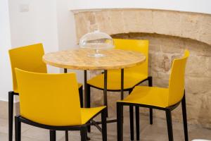 una mesa y sillas con sillas amarillas frente a una chimenea en PALAZZO NICOLAUS del BORGO ANTICO, en Bari