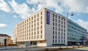 Premier Inn Nürnberg City Opernhaus في نورنبرغ: مبنى أبيض كبير مع علامة أرجوانية عليه