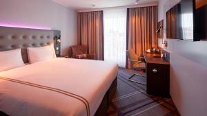 une chambre d'hôtel avec un grand lit et un bureau dans l'établissement Premier Inn Nürnberg City Opernhaus, à Nuremberg