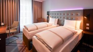 a hotel room with two beds and a desk at Premier Inn Nürnberg City Opernhaus in Nürnberg