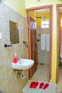 a bathroom with a sink and a shower with red slippers at Four seventy in Meru