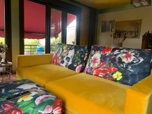 a yellow couch with floral pillows in a living room at Mandatory Stop House with Private Pool in Llanera