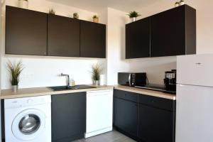 a kitchen with black cabinets and a washing machine at Esprit du Sud - Terrasse & Parking in Brignoles